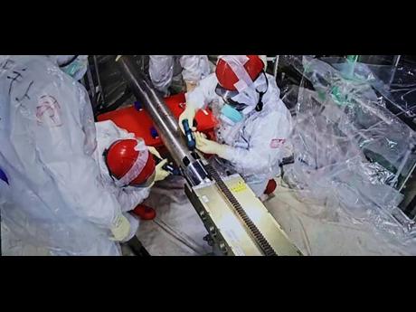 In this photo released by Tokyo Electric Power Company Holdings (TEPCO), monitoring workers rearrange the push-in pipes, at the Fukushima Daiichi nuclear power plant in Okuma, Fukushima prefecture, northern Japan.