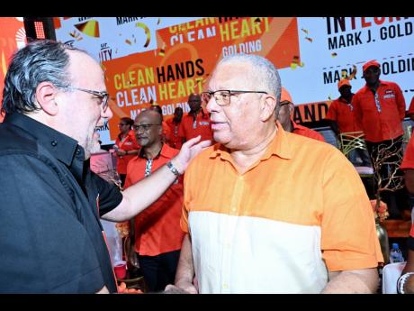 PNP President Mark Golding (left) greets his predecessor, Dr Peter Phillips, at the party’s 86th annual conference.