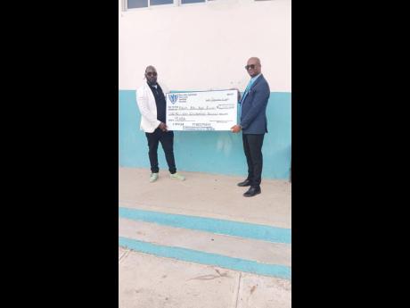 PRINCIPAL of Edwin Allen High School, Jermaine Harris (left), receives a cheque of $1.6 million from Dallas Harris, chairman of Past Edwin Allen Ballaz Association recently.