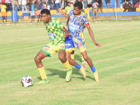 B.B. Coke High School’s Otis Powell (left) shields the ball away from St Elizabeth Technical High School’s Jordan Blake during their ISSA/WATA daCosta Cup football game at the STETHS Sports Complex yesterday.