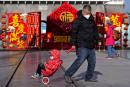 A man pulls a child past a Lunar New Year decoration on display at the Qianmen pedestrian shopping street, a popular tourist spot in Beijing.