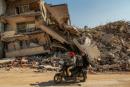 Men ride a motorcycle past destroyed buildings in Samandag, southern Turkey, on February 22. 