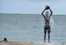 A man catches water from the sea with a paint tin as he cools down along the Kingston waterfront earlier this year.