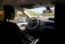 A Waymo minivan moves along a city street as an empty driver’s seat and a moving steering wheel drive passengers during an autonomous vehicle ride in Chandler, Arizona.